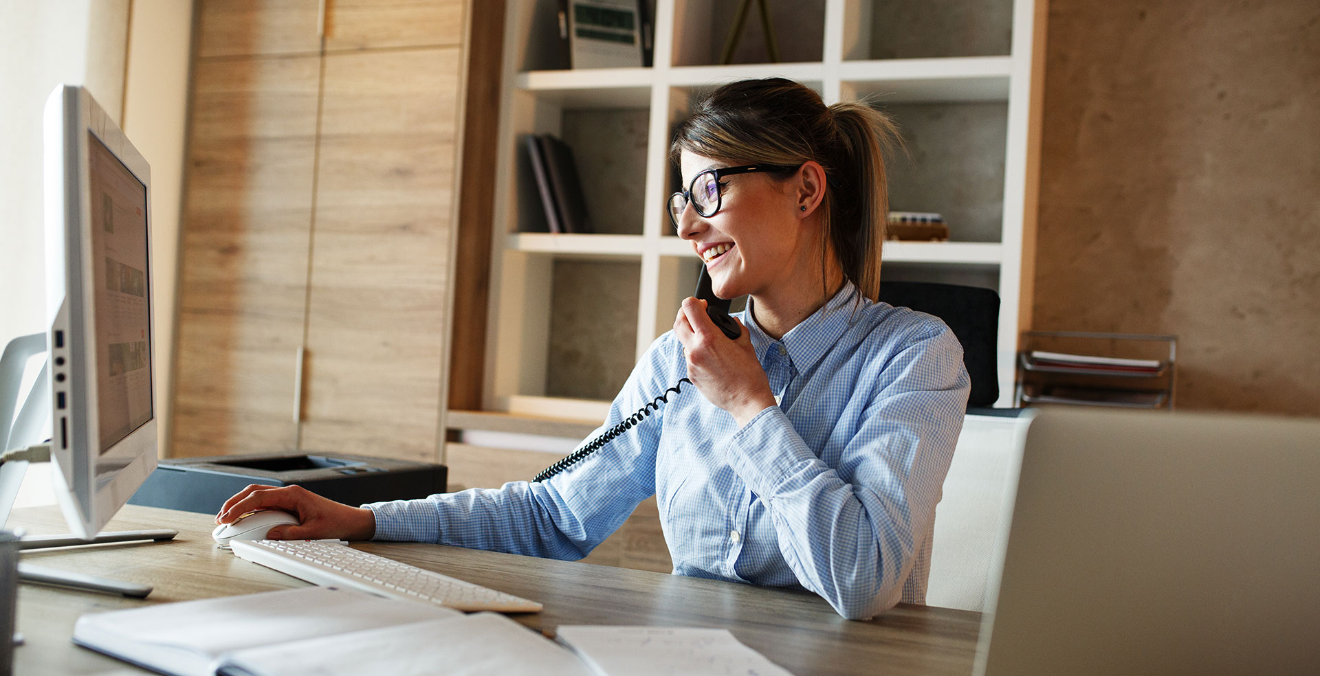 Femme au téléphone devant un ordinateur de bureau