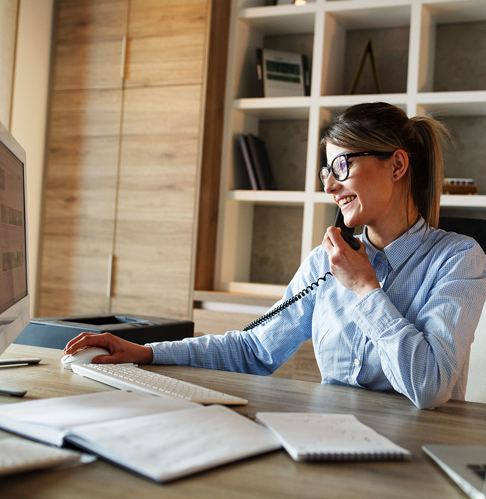 Femme au téléphone devant un ordinateur de bureau