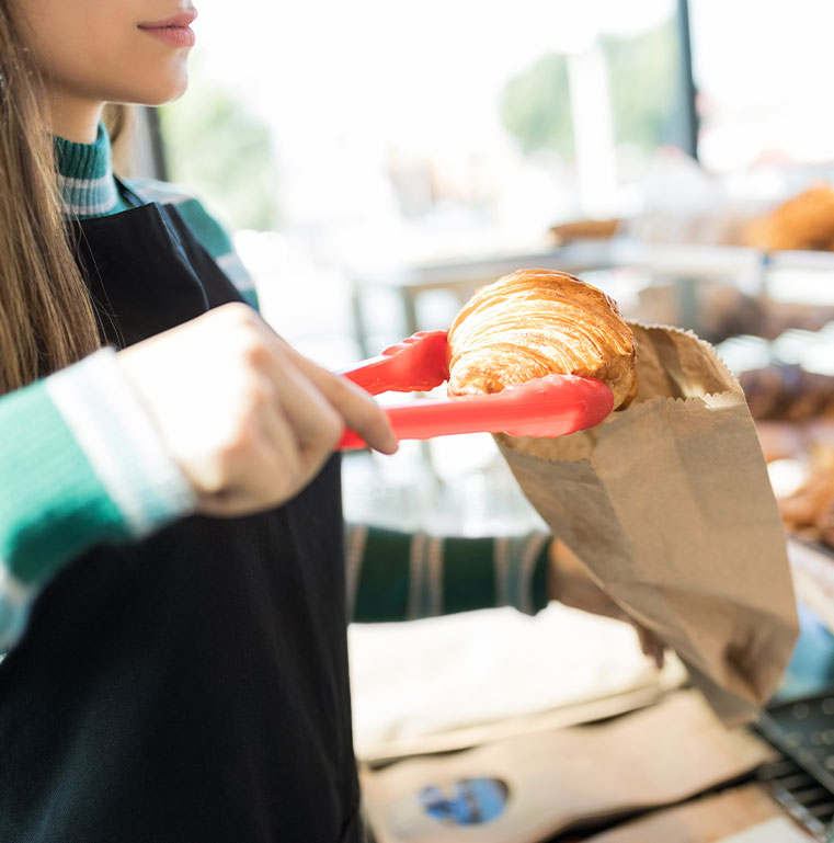 Boulangère empaquetant un croissant dans un sac